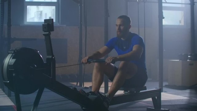 Slow motion men training rowing in gym with exercises machines and pull rope