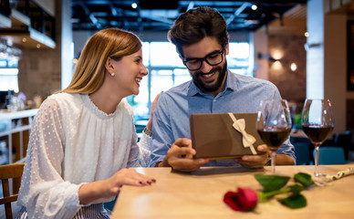 Birthday present for a boyfriend. Romantic couple sitting in the cafe and drinking red wine. Dating, love, relationships