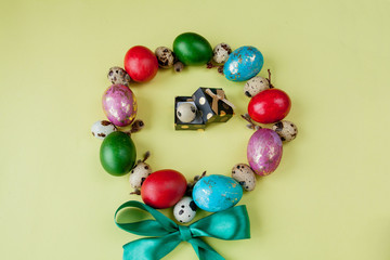 Gift and painted eggs Easter Frame in circle shape on a yellow background. Copy space, Top view