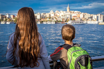 Two kids looking to cityscape of Istanbul with silhouette of Gal