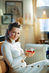 happy modern woman near radiator and warming with tea cup