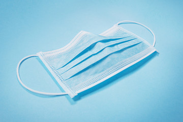 Surgical face mask laying on blue background