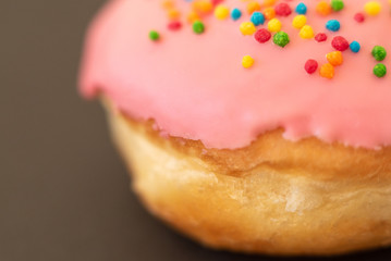 Delicious pink donut on black background close-up.
