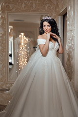Fototapeta premium Beautiful bride is trying on an elegant wedding dress in modern wedding salon. Beautiful and fashion bride with glamour makeup and hairstyle