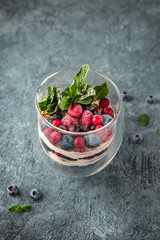 Dessert made of biscuit, chocolate with berries and fruits. Souffle cake in a glass. On a turquoise background.  Sea mood concept.