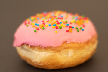 Delicious pink donut on black background close-up.