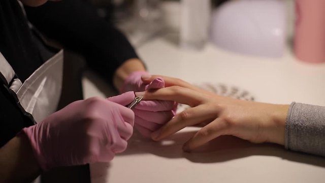 Professional manicurist removes dry cuticle skin near nails cutting it with scissors. Closeup video of professional manicure at beauty salon