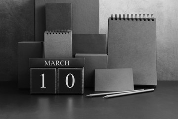 March 10th. Day 10 of month. Wood cube calendar with date month and day. Trendy classic black color. Lot of empty pages template for daily notes.