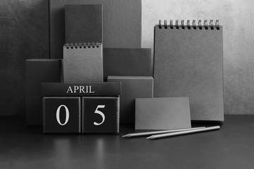 April 5th. Day 5 of month. Wood cube calendar with date month and day. Trendy classic black color. Lot of empty pages template for daily notes.