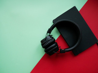 Minimalism online listen to books concept. Audiobook Book with headphones on colored background.