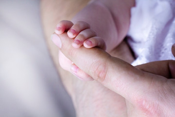 A little baby holding the finger of the father. A father's love for the baby. Care, concern, tenderness, joy.