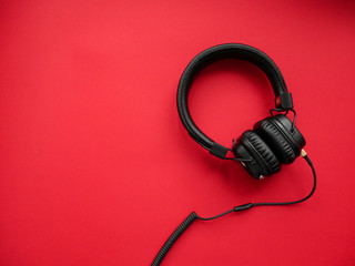 Classic black wired headphones on colored paper background. Retro style. 80s. Pop culture. Top view.