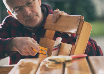 Man varnishing chair in garden