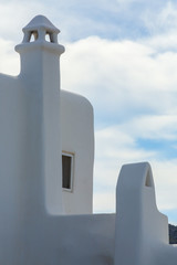 Old Mediterranean architecture house with chimneys and cloudy blue sky at back, in Mykonos, Cyclades, Greece