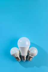 Three white led energy saving led light bulbs on a blue background.