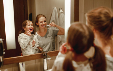 health and hygiene of the oral cavity. mother and child daughter brush their teeth in   bathroom in...