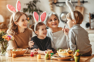 Happy easter! family mother, grandmother and children paint eggs for holiday.