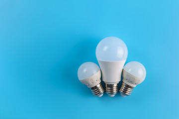 Three white led energy saving led light bulbs on a blue background.