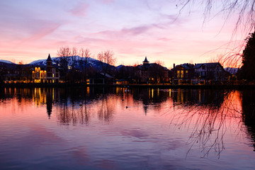 Sunset with orange clouds and lake reflection on a winter landscape silhouette in Puigcerdà, Catalonia