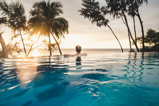 Rear view of woman in infinity pool at sunset, Nai Thon Beach, Phuket, Thailand