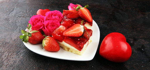 strawberry cake and many fresh strawberries on rustic table with hearts and roses for valentines day.