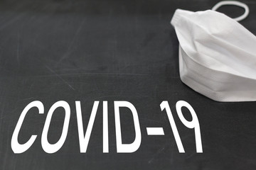 Face mask on blackboard with Covid-19 text
