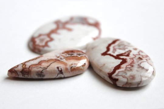 Crazy Lace Agate mineral (banded chalcedony, microcrystalline quartz) with red and brown frilly pattern, mined in Mexico. Oval shaped polished cabochon is ready for setting in jewellery.