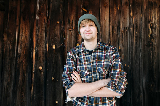 Portrait of confident man wearing wooly hat at wooden wall