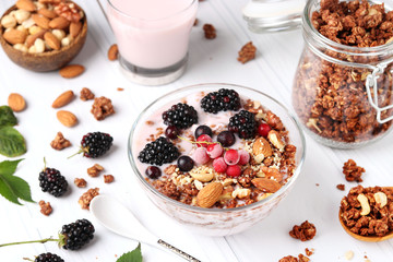 Granola crispy honey muesli with natural yogurt, fresh berries, chocolate and nuts in a bowl against a light background, healthy food, close-up