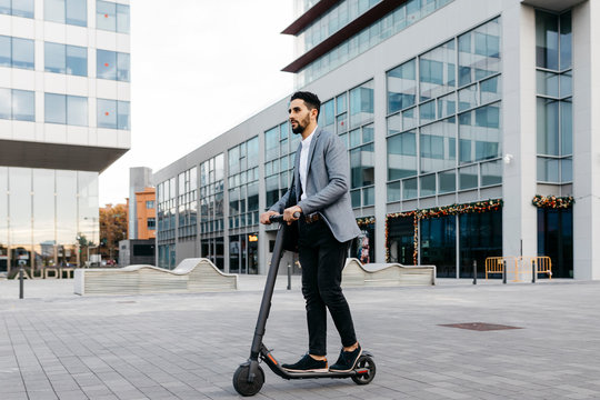Casual young businessman riding electric scooter in the city