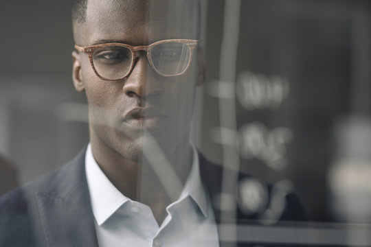 Portrait of young businessman looking at diagram on glass pane