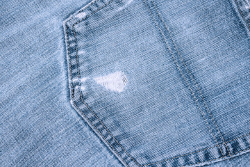 Blue denim texture background. Ripped jeans fabric closeup