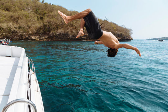 Young man jumping from a boat, Lembongan island, Bali, Indonesia