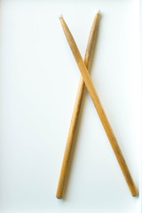Two crossed wooden drumsticks on a white background.