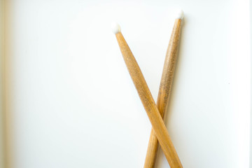 Two crossed wooden drumsticks on a white background.