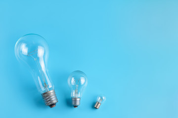 Big, normal and tiny classic incandescent lamps on a blue background.