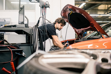 Car mechanic in a workshop working at car