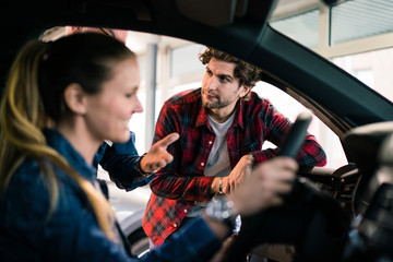 Car dealer showing car to couple in showroom