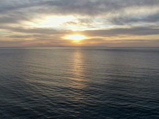 Aerial view of Pacific ocean colorful sunset, facing the sun with reflection on the ocean and deep...