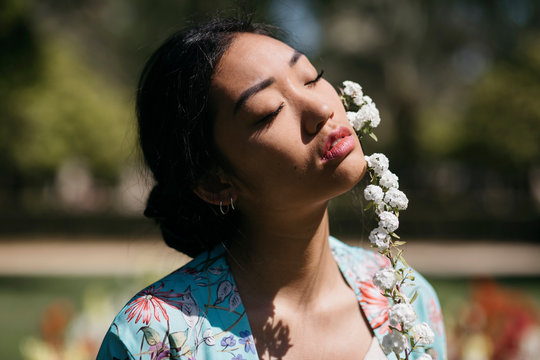 Beautiful young woman with flower in a public garden in spring