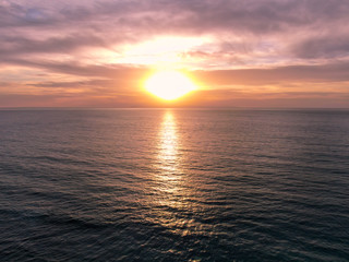 Aerial view of Pacific ocean colorful sunset, facing the sun with reflection on the ocean and deep...