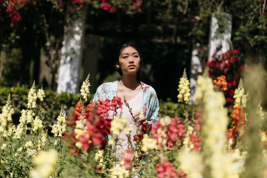 Beautiful young woman surrounded by flowers in a public garden in spring