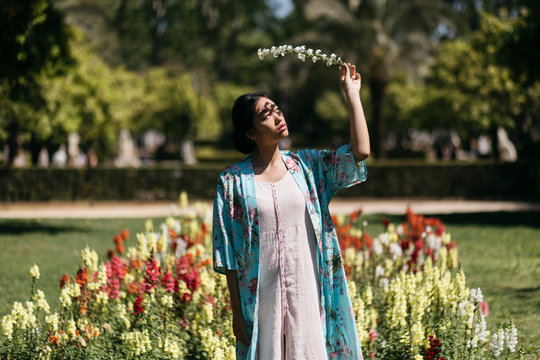 Beautiful young woman holding flower in a public garden in spring
