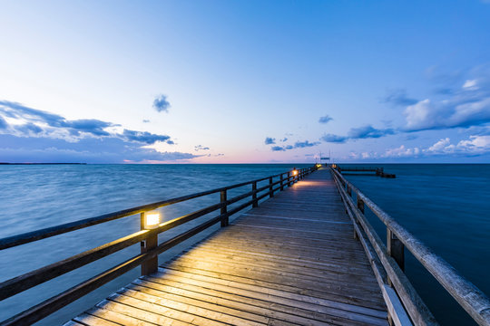 Germany,?Mecklenburg-Western Pomerania, Prerow, Illuminated pier at dusk with clear line of horizon over Baltic Sea in background