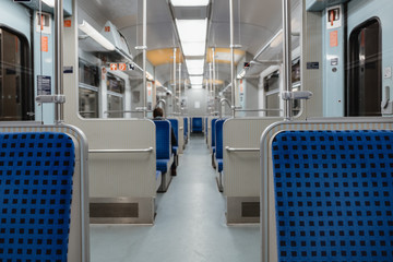 Naklejka premium Interior view of a corridor inside passenger trains with blue fabric seats of German railway train system. Empty vacant passenger car inside the train.