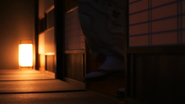 Slow motion of traditional Japanese house ryokan with tatami mat floor, shoji sliding paper doors and woman in kimono and geta shoes tabi socks walking in corridor hall room