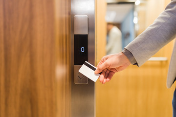 Man holding key card on sensor to open elevator door in modern building or hotel. © zphoto83