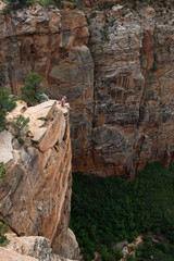Girl dangling her legs off a sheer sandstone cliff