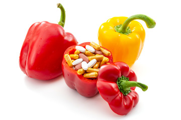 Nourishing diet and replenish vitamins, minerals and supplements through healthy organic food concept with bell peppers full of vitamin and mineral pills isolated on white background