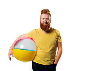 Air ball in hand a young man with glasses with a yellow rim on his face on white isolated.Summer bright yellow photo. Red bearded guy.travel and summer beach vacation concept.